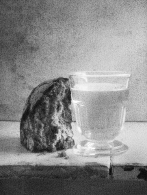 Schwarzweißfotografie von Hubertus Schüler, Brot mit Wasserglas auf einem Tisch